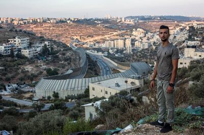 Taysir Saify, 20, stands on a hill in the Palestinian city of Beit Jala that overlooks Jerusalem in the early evening . Below the hilly landscape , is a portion of Israel's concrete separation barrier wall that hugs over the area of the main road Route 60 that connects Jerusalem to the West Bank. Heidi Levine for The National