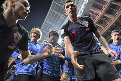 Croatia's forward Mario Mandzukic, centre, offers to help AFP photographer Yuri Cortez after he fell on him with teammates while celebrating their winner against England. Yuri Cortez / AFP Photo