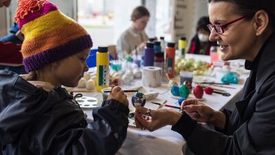 Myroslava Perevalska (R), an artist who fled Kyiv, helps a Ukrainian girl paint Easter eggs in Berlin. Getty Images