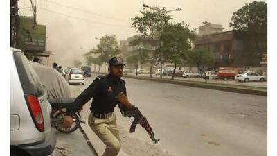 A policeman, running towards a firefight at the Ahmedi mosque, in Lahore's Garhi Shahu neighbourhood, takes cover after an explosion on Friday.