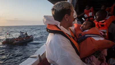 A member of the Migrant Offshore Aid Station helps refugees waiting to be let off the island of Lampedusa, south of Sicily. Getty Images