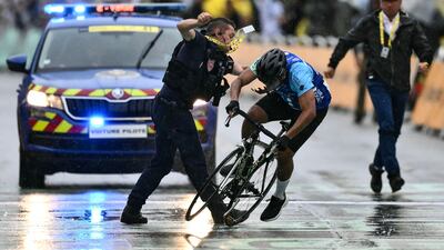 A French Republican Security Corps officer tackles a man attempting to cycle across the finish line minutes before the final sprint of the 112th edition of the Tour de France. AFP