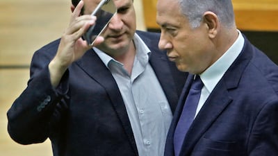 Israeli-Arab Knesset member Ayman Odeh (L) uses a phone to take a close-up picture of Prime Minister Benjamin Netanyahu in the main Knesset chamber in Jerusalem on September 11, 2019. A rare clash erupted between Netanyahu and Joint List Chairman Odeh on September 11 at the Knesset during a discussion ahead of a vote on a controversial, Likud party-sponspored bill to allow cameras in polling booths. / AFP / Gil COHEN-MAGEN
