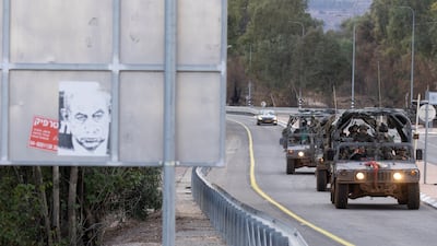 Israeli army vehicles pass by a protest sign showing a photo of Israeli Prime Minister Benjamin Netanyahu as they move along the northern border.