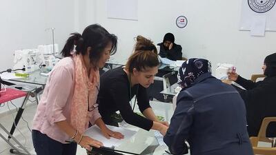 Maria Iqbal, centre, and Carla Bygrave, teaching a former lawyer and now Syrian refugee and widow, how to make a tote bag from scratch.