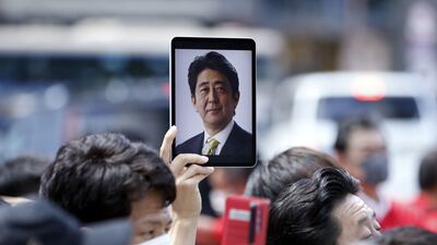 A photograph of former Japanese prime minister Shinzo Abe is held in the air at a campaign event on Saturday. Abe's death has raised questions about security for public figures. Photo: Bloomberg