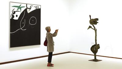 A woman takes a picture of a sculpture The Russet-feathered Bird announces the Apparition of the Dazzling Beatuiful Women by Spanish artist Joan Miro as she stands next to his painting Women in front of Schooting Star during an exhibition in Vienna September 11, 2014. The Miro exhibition From Earth to Sky runs from September 9 until January 11, 2015 in the Albertina Museum in Vienna. Leonhard Foeger/ Reuters