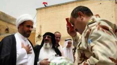 An Iraqi army officer (right) receives flowers and a Quran from representatives of Muqtada al Sadr in Basra, Iraq, yesterday.