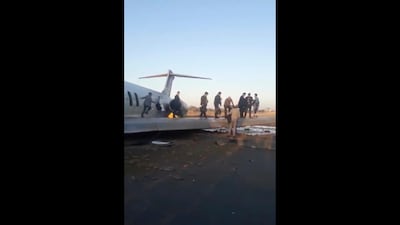 Passengers use a wing of the crashed plane to reach safety in Mahshahr, Iran. AP