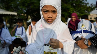 A Malaysian Muslim girl from the Little Caliphs kindergarten, clad in white hijab which is the traditional attire for Muslim women performing the Haj pilgrimage, holds mock stones made from papier mache before performing the ritual of stoning the devil during an educational simulation of the pilgrimage in Shah Alam, outside Kuala Lumpur.