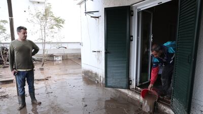 Residents of Agia Anna pour buckets of muddy water from their home in Evia. EPA