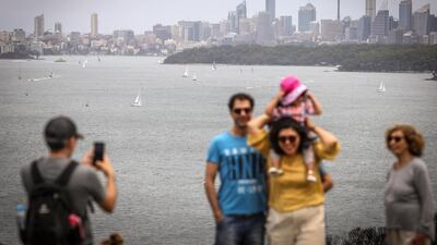 People pose for photographs in front of yachts and ferries as they sail on Sydney Harbour during Boxing Day this year. Human contact has been a challenge for most people in a year ravaged by coronavirus pandemic. Getty Images