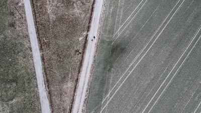 Two hikers walk between fields, covered with a soft blanket of snow, on the outskirts of Anspach, Germany. dpa via AP