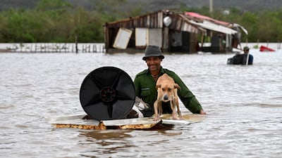 A Cuban farmer rescues his dog and some belongings from his flooded house after Hurricane Melissa passed through San Miguel de Parada, in Santiago de Cuba province. AFP