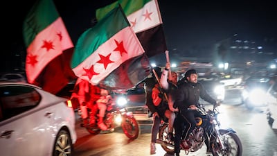 Syrians in Damascus wave the opposition's flag as they celebrate the fall of Bashar Al Assad on Wednesday. EPA