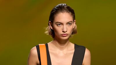 High-waisted tan leather trousers and a jacket that can be carried over the shoulder with a strap. At Hermes spring/summer 2023. AP