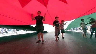 The Jordanian government has raised fuel prices twice in three months. Above, children walk under a giant flag of Jordan during a protest on Friday. Mohammad Hannon / AFP