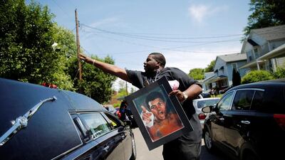 A man throws a rose on to the hearse carrying the remains of Muhammad Ali during the funeral procession for the three-time heavyweight boxing champion in Louisville, Kentucky, on June 10, 2016. Carlos Barria / Reuters