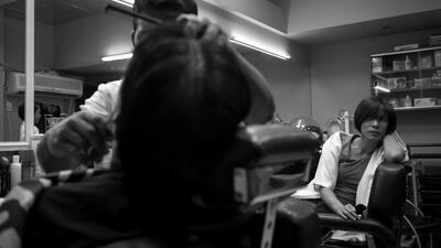 A man gets a haircut at a saloon (barber shop) in the Al Zahiyah area of Abu Dhabi while another barber looks on. Brian Kerrigan / The National