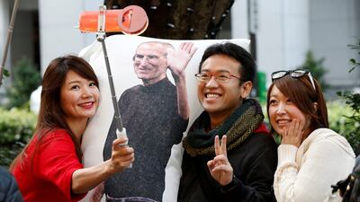 Ayano Tominaga, left, and other customers pose for a selfie photo with a cushion printed with a portrait of Apple co-founder Steve Jobs on it, as they wait in queue for the release of Apple's new iPhone X in front of the Apple Store in Tokyo's Omotesando shopping district, Japan. Toru Hanai / Reuters