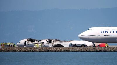 An airliner passes the wreckage of an Asiana Airlines Boeing 777 which crash landed at San Francisco International Airport in San Francisco. Reuters/Stephen Lam