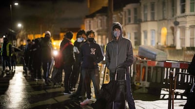 International students queue to collect food packages at the Newham Community Project food bank in east London. AFP