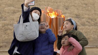 A family takes a selfie with the Olympic flame on a cauldron displayed at Ishinomaki Minamihama Tsunami Recovery Memorial Park on Friday. EPA