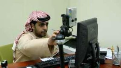 Essa Mohammed, a registration officer, takes fingerprints and a photo at the Emirates Identity Authority centre in Al Barsha in Dubai.