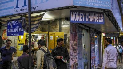 Pedestrians walk past by a currency exchange store in India's commercial capital Mumbai. The rupee, the worst performing currency in Asia this year, touched a record low at $69.0925 per dollar on Thursday as gains in oil prices threatened to stoke inflation and worsen the nations domestic and external finances. Photographer: Dhiraj Singh/Bloomberg