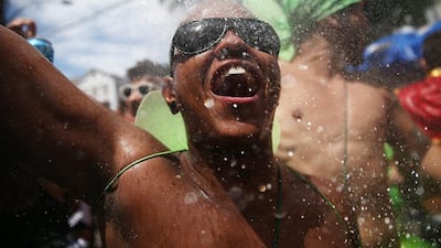 A reveller exalts while being sprayed by water from a resident during the ‘Ceu na Terra’ street carnival bloco. Mario Tama / Getty Images