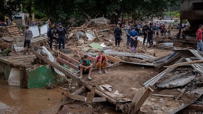 People survey the damage caused by the overflow of the Los Patos river, in Tejerias. EPA