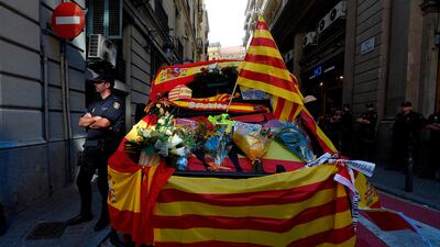 A Spanish policeman stands next to a police van decorated with Spanish and Catalan flags by protesters attending a demonstration called by "Societat Civil Catalana" (Catalan Civil Society) to support the unity of Spain on October 8, 2017 in Barcelona. Lluis Gene / AFP