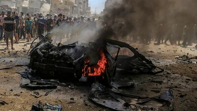 Palestinians look at a burnt-out car following an Israeli air strike on Gaza city. EPA