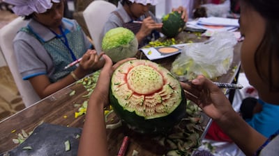Thai girls carve floral patterns into fruits during a fruit and vegetable carving competition in Bangkok. Robert Schmidt / AFP
