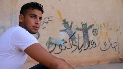 Moawiya Sayasina, the Syrian activist who started scribbling anti-Assad slogans in 2011, sits next to a graffiti drawn on the wall of a schoolyard reading in Arabic "Your turn, Doctor", in a rebel-held neighbourhood in the southern Syrian city of Daraa. Mohamad Abazeed / AFP