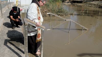 Father Patton stands by the Jordan River during a baptism.