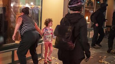 A woman pulls a child away from a protest crowd as it passes a downtown restaurant in Portland, Oregon. AFP