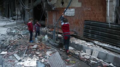 Syrian children fill plastic containers at a water pump in Arbin in the rebel-held enclave of Eastern Ghouta on February 25, 2018. Abdulmonam Eassa / AFP