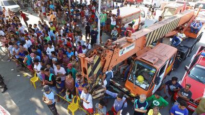 Residents look on as search operations continue at a collapsed commercial building in Porac town.