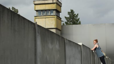 BERLIN, GERMANY - AUGUST 05: A visitor standing on a ladder looks over a still-existing section of the Berlin Wall into the so-called 'death strip,' where East German border guards had the order to shoot anyone attempting to flee into West Berlin, as an original watchtower stands behind at the Bernauer Strasse memorial on August 5, 2011 in Berlin, Germany. The city of Berlin will mark the 50th anniversary of the construction of the Wall on August 13. The Berlin Wall was originally built in 1961 by the communist authorities of East Germany in order to stop East Germans from fleeing west, and up to an estimated 245 people died trying to do so until the Wall came down in 1989. (Photo by Sean Gallup/Getty Images) *** Local Caption *** 120369697.jpg