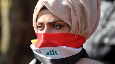An Iraqi anti-government protester using the national flag as a mask takes part in a rally near the Ministry of Higher Education in the capital Baghdad on January 14, 2020. AFP