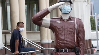 People wear protective face masks to help curb the spread of the coronavirus next to a police statue with its own mask at the Hua Lamphong Railway Station in Bangkok, Thailand. AP Photo