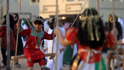 Children dressed in traditional Emirati clothes play on the swings. Ravindranath K / The National