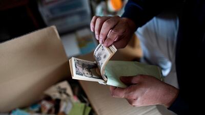 In this picture taken on June 21, 2017, a cleaning company worker finds a stack of Japanese yen notes as he cleans up a woman's apartment in Yokohama, who died alone in her apartment and was found days later. Japan's stock market may be riding at two-decade highs but sales of home safes are booming as the country's already keen savers look to stash more cash at home to avoid being hit by negative interest rates and keen-eyed tax officials. / AFP PHOTO / Behrouz MEHRI / TO GO WITH AFP FOCUS "JAPAN-INVESTMENTS-BANKING-CULTURE" BY KARYN NISHIMURA-POUPEE