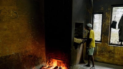 A factory worker puts a tray containing bundles of bidis, in a hot brick oven, to dry at The New Sarkar Bidi Factory in Kannauj.