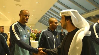Sheikh Mansour shakes hands with Manchester City player Vincent Kompany.