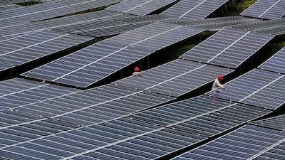 Workers check solar panels at a power station in Chongqing, China. Reuters