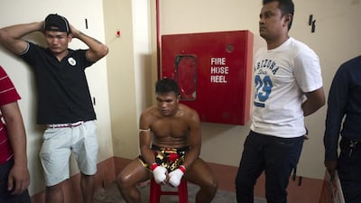 To go with MYANMAR-SPORT-BOXING,FEATURE by Athens Zaw Zaw This photo is taken on December 20, 2015 shows Lethwei martial arts fighter Tun Tun Min (C) sitting before a bout with his opponent, US national Cyrus "Black Dynamite" Washington, at the Thein Phyu boxing stadium in Yangon. A roar erupted at the Yangon ring as the home champion ploughed a right hook into his American opponent's face, crumpling him to the canvas in the opening round of the bone-crunching kickboxing bout. With head-butts among the array of painful blows permitted, Lethwei pugilists say their sport is the hardiest member of Southeast Asia's kickboxing family -- even more brutal than Thailand's better known Muay Thai. AFP PHOTO / Ye Aung THU / AFP / Ye Aung Thu
