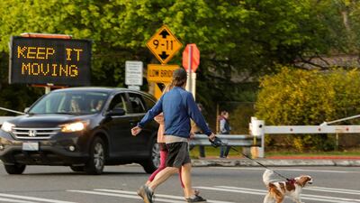 People walk their dog past a sign at Golden Gardens Park telling people to keep moving after Seattle Mayor Jenny Durkan reopened parks that were closed Easter weekend as efforts continue to help slow the spread of coronavirus disease in Seattle, Washington, US. Reuters