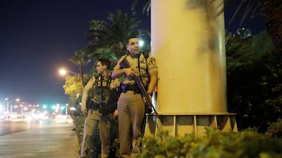 Police officers take cover near the scene of a shooting near the Mandalay Bay resort and casino on the Las Vegas Strip. John Locher / AP Photo